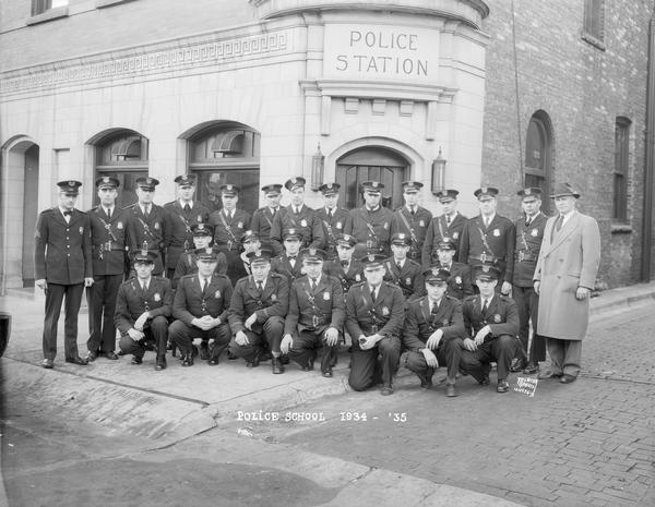Group portrait of police officers taken in front of the Madison Police Station at 14-16 South Webster Street. They are members of the Police School 1934-1935, Night Force.