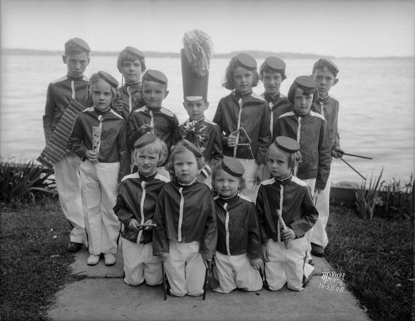 Group portrait of children's rhythm band in uniform, posing on the lake shore terrace at Rutledge and S. Brearly Streets. They are getting ready to play and raise money for the Kiddie Camp fund.