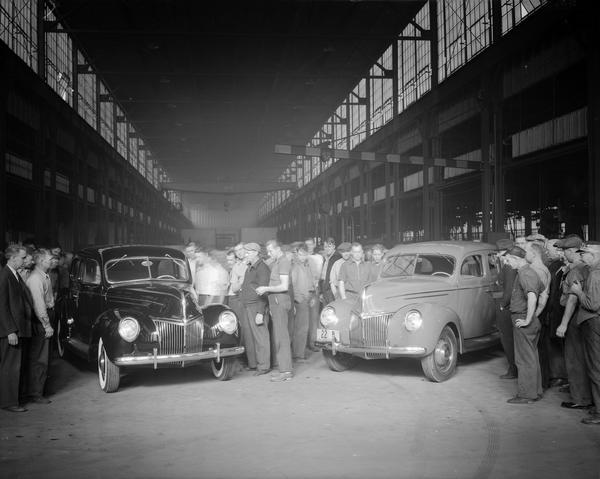 Crowd of workers viewing two new Ford cars in the Madison Kipp Corp. plant, 201-231 Waubesa Street.