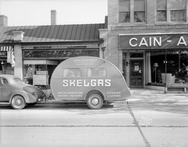 Skelgas trailer, with two gas tanks being pulled by an automobile, stopped in front of Suburban Gas & Appliance Co., 1923 Monroe Street.