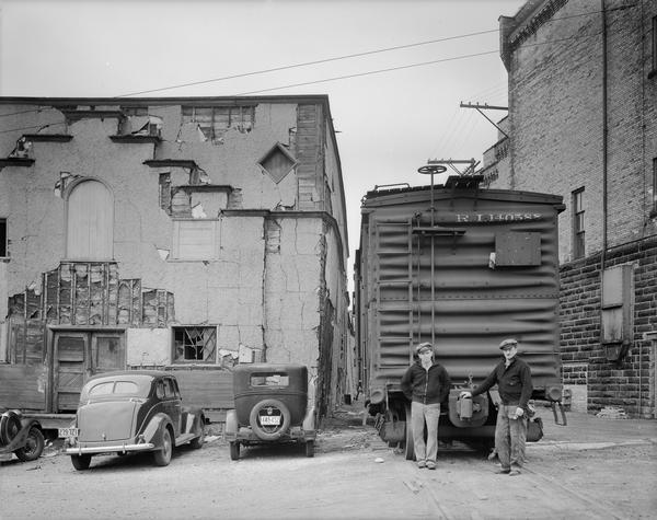 Two men are standing next to a railroad car at the rear of the Fauerbach Brewing Company at 651-653 Williamson Street.