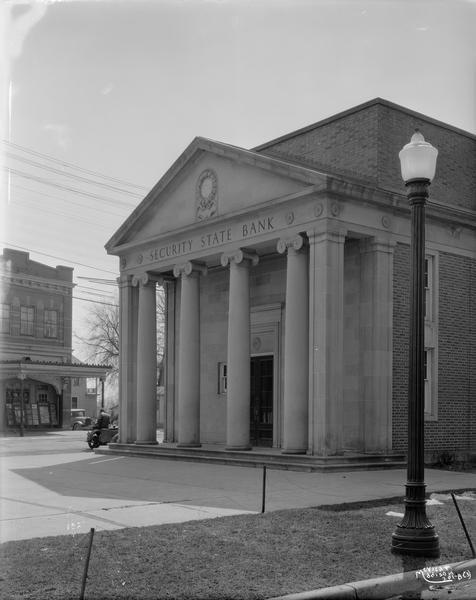 Security State Bank at 1965 Atwood Avenue, with a lamppost in the foreground. The Gem Theater, later known as the Palace Theater at 1953 Winnebago Street, is in the background.