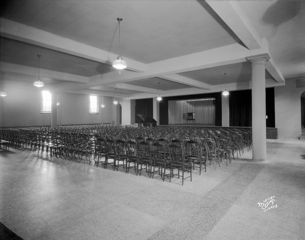 First Congregational Church dining room, with rows of chairs, and showing a grand piano in front of a stage in the back of the room, at 1609 University Avenue.