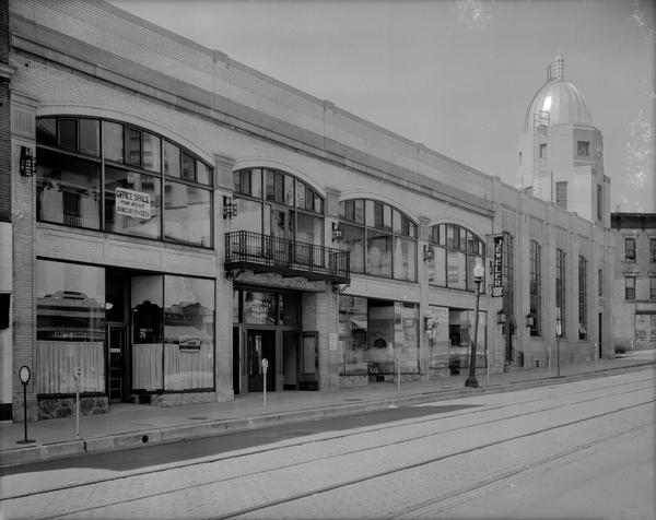 Odd side of the 100 block of King Street , from left to right, Interstate Finance Corp., 113 King Street; entrance to Capital City Bank Building, 111 King Street, also known as King Street Arcade; Arcade Barber Shop, 109 King Street; Kempf's pet supplies, 107 King Street; Charlier & Son jewelers, 107 King Street;  and Fidelity Assurance Association, 101 King Street, with parking meters at the curb.