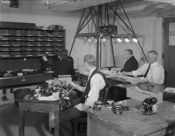 Three men are making microfilm copies of birth records in the microfilm department at the Wisconsin State Office Building (Capitol Annex), 1 West Wilson Street.