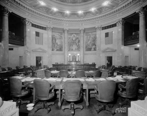 Wisconsin State Capitol Senate chamber showing seating for senators, and a three-panel mural: "The Marriage of the Atlantic and Pacific" by Kenyon Cox.