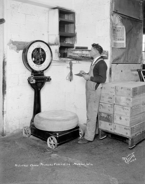 A worker weighs a wheel of cheese on a Toledo scale for the National Cheese Products Federation.