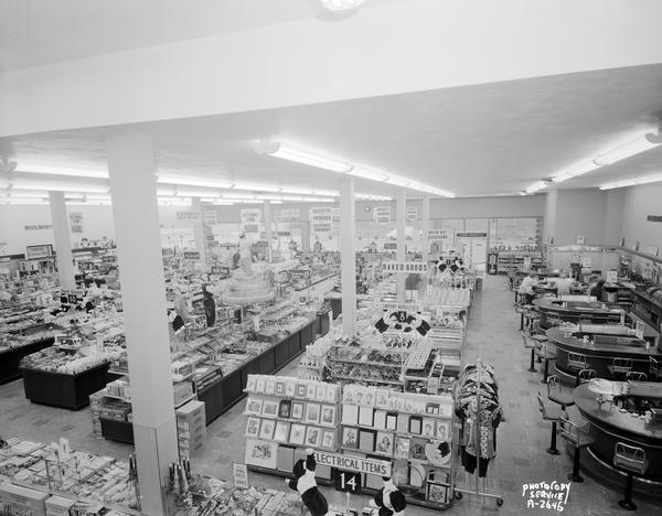 Interior of the new, self-service Woolworth's variety store at 2-8 West Mifflin Street. The view is toward the front from the balcony, showing main floor sales area, with merchandise on display counters and a lunch counter.