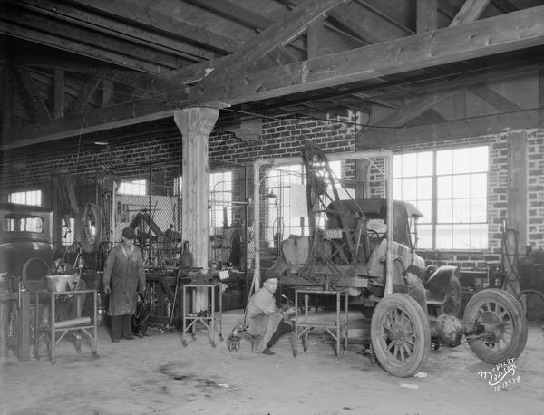 The Capital Buick Co. machine shop, 750 E. Washington Avenue, with two mechanics repairing an automobile.