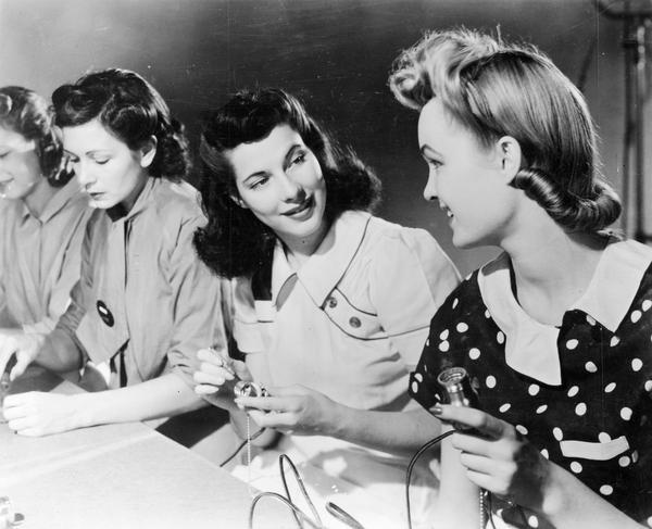Four women assembling light sockets.