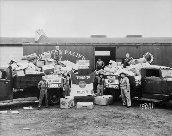 Boy Scouts, Troop #20, from Christ Presbyterian Church, in front of a Northern Pacific railroad freight car, with two truckloads of salvaged paper they've collected and brought to the collection depot.