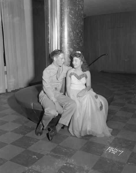 A couple attending the "Moonlight Formal" share a romantic moment on a circular bench in the lobby outside the Union Theater at the University of Wisconsin Memorial Union.