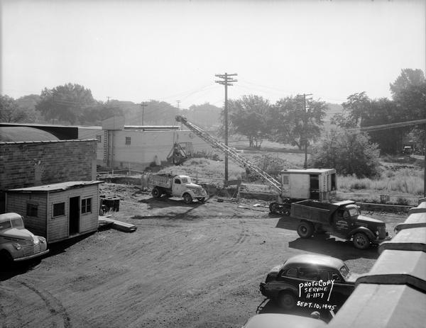 Elevated view of a Findorff truck and earthmover and Madison Sand and Gravel truck standing ready to excavate for an addition to the Red Dot Foods, Incorporated, potato chip factory, 1441 East Washington Avenue.
