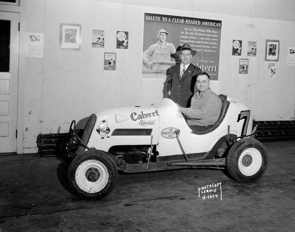 A driver sits in a small promotional race car with a "Calvert Special" logo on its side at Plymouth Liquors, 2717 Atwood Avenue.