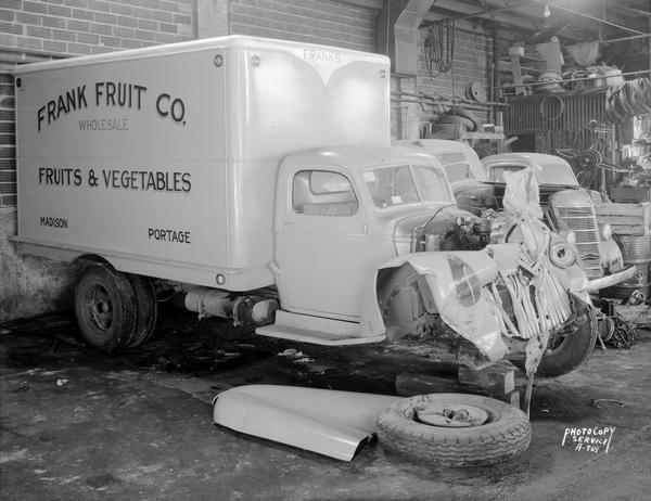 A Frank Fruit Co. truck sits in a garage after a traffic accident that destroyed the front end of the vehicle.