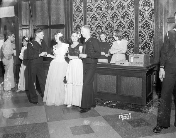 Young women in formal dress and naval cadets in uniform attend the "Moonlight Formal" at the Tripp Commons in the Memorial Union on the University of Wisconsin-Madison campus.