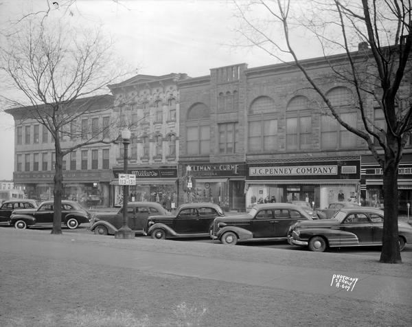 Cars parked along East Main Street on Capitol side showing Kresge's Building, Miller's Women's Clothing, Feltman & Curme Shoe Store, and J.C. Penney's Department store.