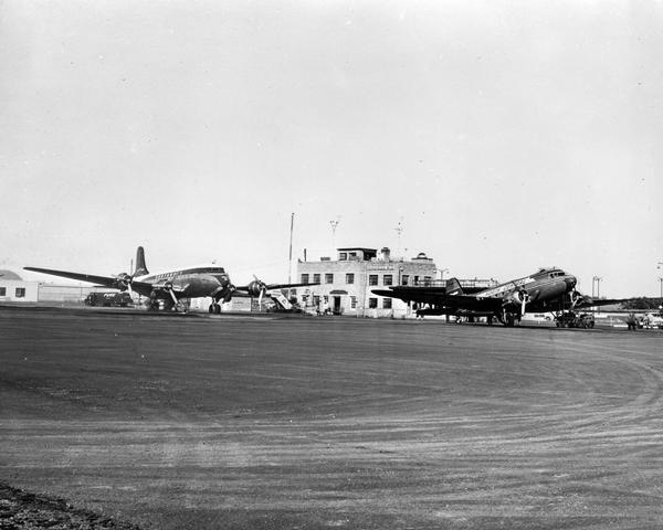 Northwest and North Central airplanes, a DC3 and a Conair, in front of the terminal building of the Madison Municipal Airport.