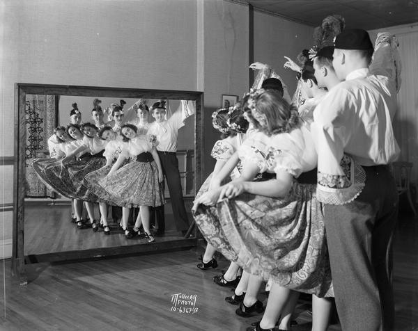 Five couples wearing folk costumes and tap shoes posing in front of a mirror for the Hazel Conlon School of the Dance.