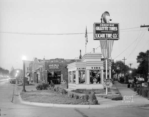 A view of the Licari Tire Company, 767 West Washington, with a Phillips sign in the foreground, and a Gillette Tire Company sign with the company's slogan: "A Bear For Wear." Gillette tires were manufactured in Eau Claire, Wisconsin. In the far distance is the Wisconsin State Capitol.