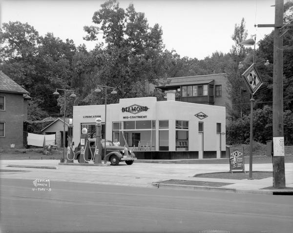 Alf H. Olson D-X Diamond service station, 2035 University Avenue and Forrest. The back side of Heights Manor Apartments, located at 2024 Kendall Avenue is in the background.