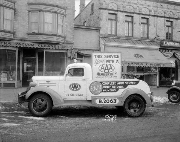Tow truck of Gil & Ray Schultz parked in front of American Automobile Association office at 724 University Avenue. On the truck is a sign that reads: "This service yours with a AAA membership." The American Automobile Association was formed in 1902 as a national. non-profit motoring organization. Also behind the truck is the Eureka Vacuum Cleaner Company.