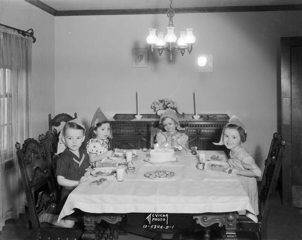 Children's birthday party at 906 Brittingham Boulevard, with participants wearing party hats and sitting at a table with a birthday cake.