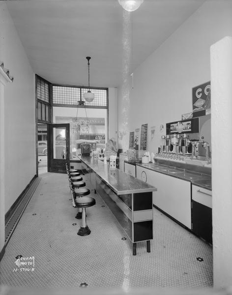 An interior view of McCoy's Ice Cream Parlor, 507 State Street, with soda fountain & bar. The front door and front window are in the background.