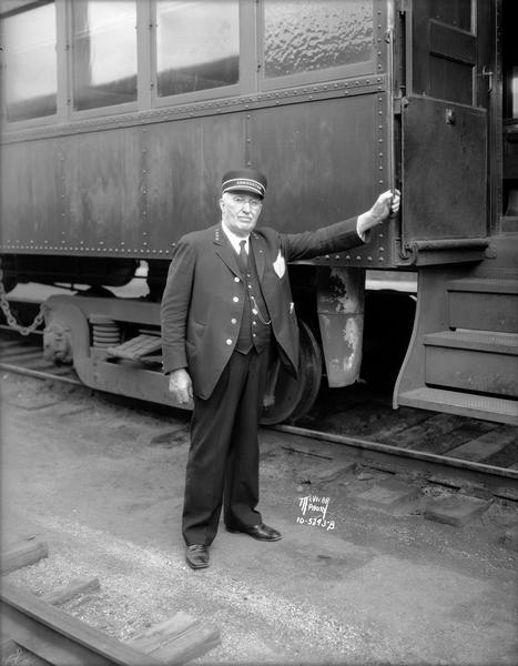 James M. LaValle, Winona, Minn., posing next to a passenger car. Mr. LaValle had the most seniority in the Madison Division of the Chicago and Northwestern Railroad.