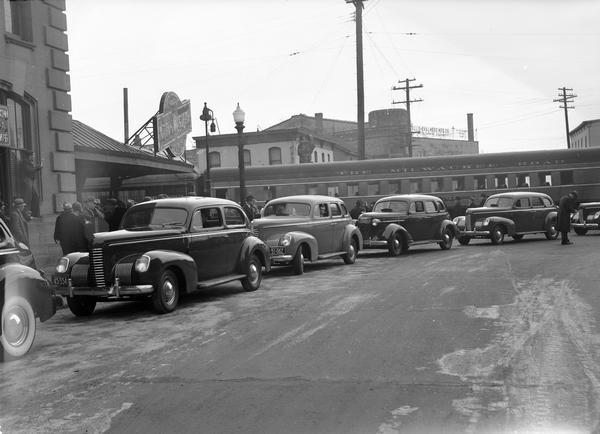 Four Nash automobiles at Chicago & Northwestern Railroad Station, 219 S. Blair Street, with Milwaukee Road passenger car in the background.  The occasion is Governor Julius P. Heil's inauguration.