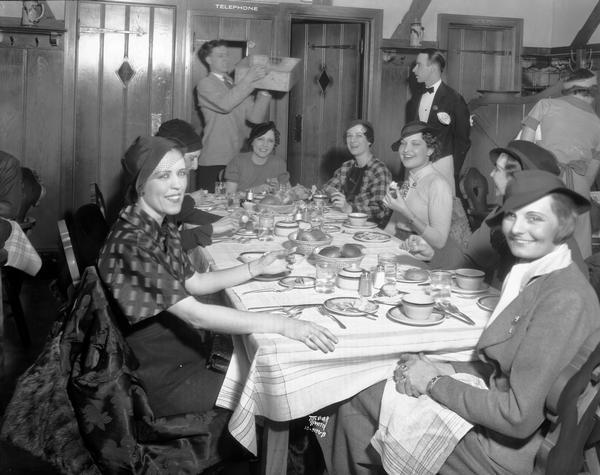 Seven show girls, wearing hats, from the Orpheum's "Spices of 1935" show, sitting at a table at Hommel's Heidelberg Hofbrau Restaurant, 20 West Mifflin Street.