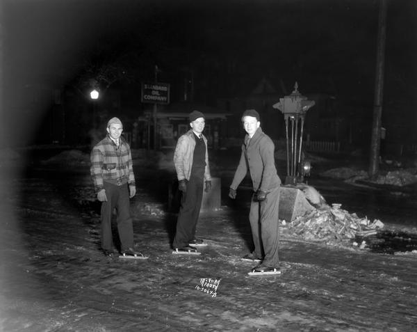 Winter scene with boys ice skating on University Avenue, Madison, Wisconsin, after an ice storm. From left to right: G. Halamka, J.A. Zimmerman, A.J. Jark.