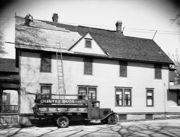 Durfee Brothers Roofing Co. truck in front of a home, Jos. P. Slightam residence) at 341 West Wilson Street, with a roofer installing shingles on the steeply-pitched roof.