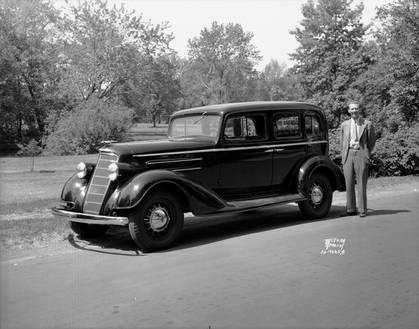 Ray Perkins, President of The Wisconsin Engraving Company, standing beside his new Oldsmobile sedan which he won at the Zor Shrine Temple's Past Potentate ball.