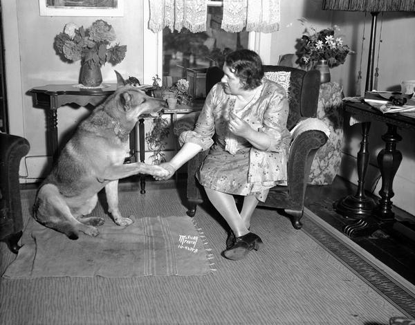 Olga Laube sitting in her living room at 604 East Johnson Street with her trained German Police dog "Barry," who can add, subtract, multiply, spell, and do many other things.