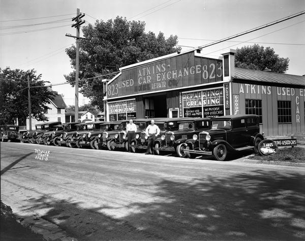 Atkins Used Car Exchange in a Trachte building, 823 E Mifflin Street, with car dealers standing along side several used cars on display.