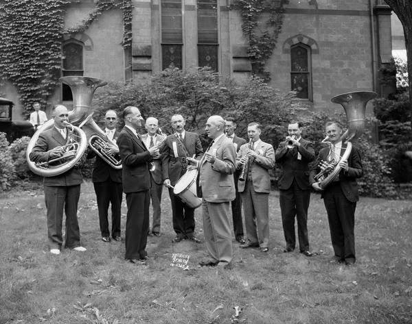 A reunion of eight members of the 1915 University of Wisconsin world's fair band with their instruments, director Charles Mann, and current (in 1935) U.W. Band Director Ray Dvorak.