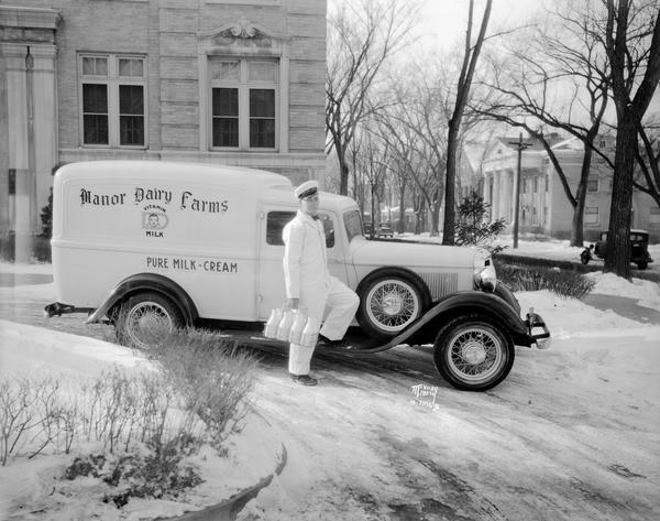 Manor Dairy truck and uniformed driver with milk in front of the dairy office in Kennedy Manor apartment building, 1 Langdon Street.