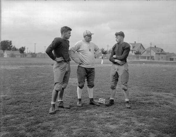 East High School football coach, A.J. "Hunk" Barrett conversing with two of his football players on the practice field.