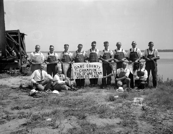 Dane County tug of war champion team, dressed in overalls, with ropes used in competition. The team went to the 1934 Chicago World's Fair.