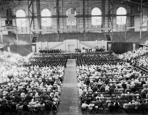 Speakers, graduates, and guests are seated in the University of Wisconsin-Madison Field House, the venue for the University of Wisconsin-Madison commencement ceremonies.