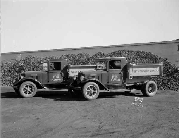 Two new West Kentucky Coal Co. 1.5 ton International trucks in front of piles of Wesco Royal Red Ash coal at the coal yards at 1433 Monroe Street.