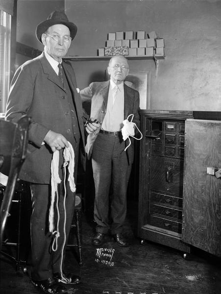 A.A. Linde, cashier, and Carl Linde, assistant cashier of DeForest State Bank, display the ropes and gag used during a robbery of the bank.