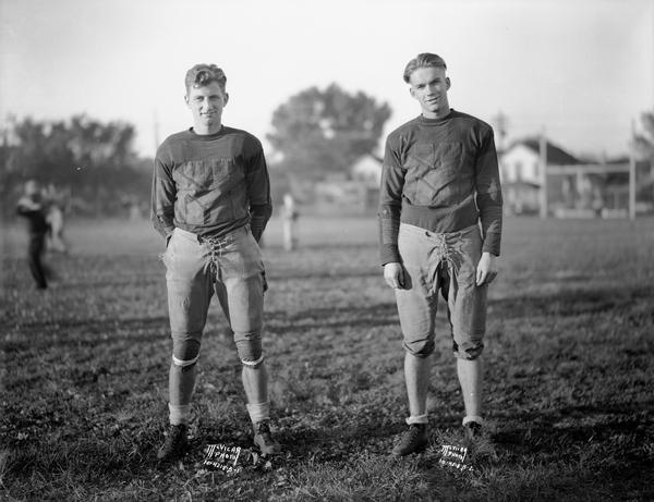 Two Central High school football players, Captain of the team Bid Smith on the right, and an unknown teammate on the left, poing for a portrait on the playing field.

