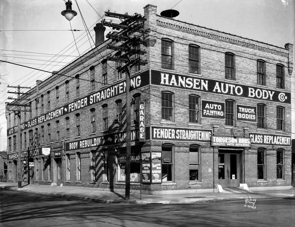 The Hansen Auto Body Company building, 113 - 123 South Blair Street with signs advertising the services of fender straightening and glass replacement.