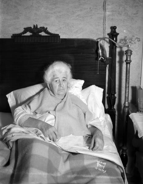 Portrait of elderly Mrs. Hugh O'Neill, lying in bed after losing her life savings of $610, which had been in a bag pinned to her undergarments. 917 Chandler Street.