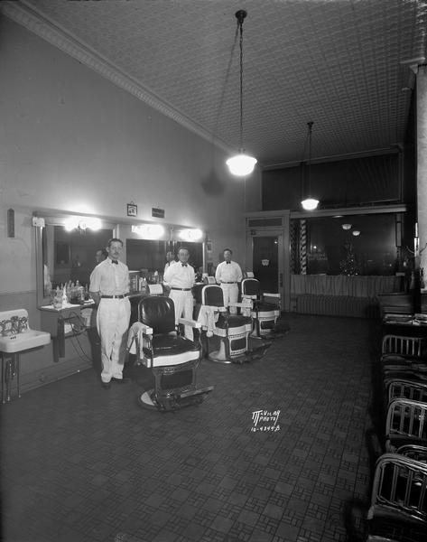 Interior view of Kretlow's Barbershop, 109 W. Mifflin Street, with three barbers: left, "Duke" Ahern, center, Burt Bruce, and owner Ray Kretlow, standing next to their barber's chairs.