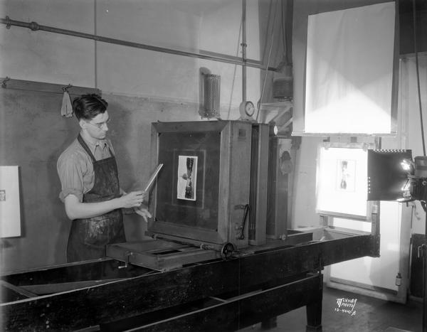 A man in the camera room at the Wisconsin Engraving Co. plant, 109 S. Carroll Street, is making a halftone negative, the first step in making a photo engraving plate.