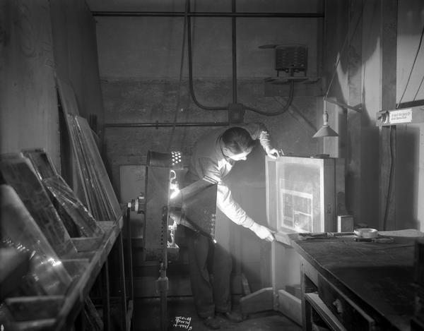 A man exposing a negative onto a zinc plate, in preparation for making a zinc etching at Wisconsin Engraving Co., 109 S. Carroll Street.