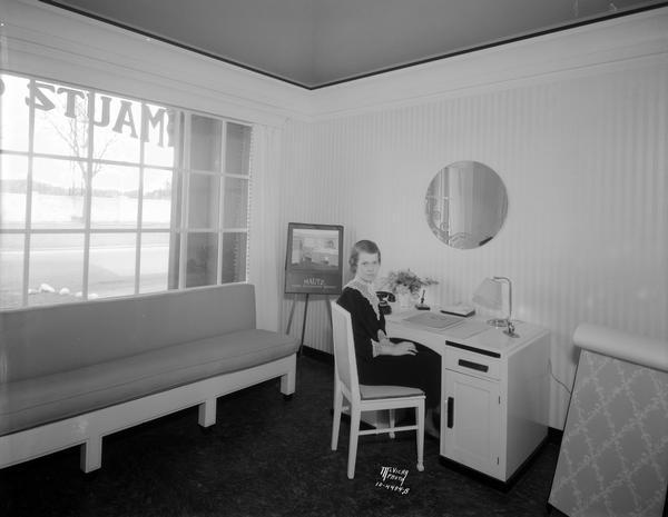 Beatrice Conley, staff director of the Mautz Home Decoration Service, sitting at a desk in her office at 939 East Washington Avenue.